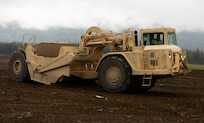 Alaska Army National Guard Sgt. Zachary Tomasetti, a horizontal construction engineer assigned to the 910th Engineer Support Company, operates a wheeled tractor-scraper to transport dirt to different land posts that will later be surveyed as a part of annual training on Joint Base Elmendorf-Richardson, Alaska, Aug. 8, 2023.