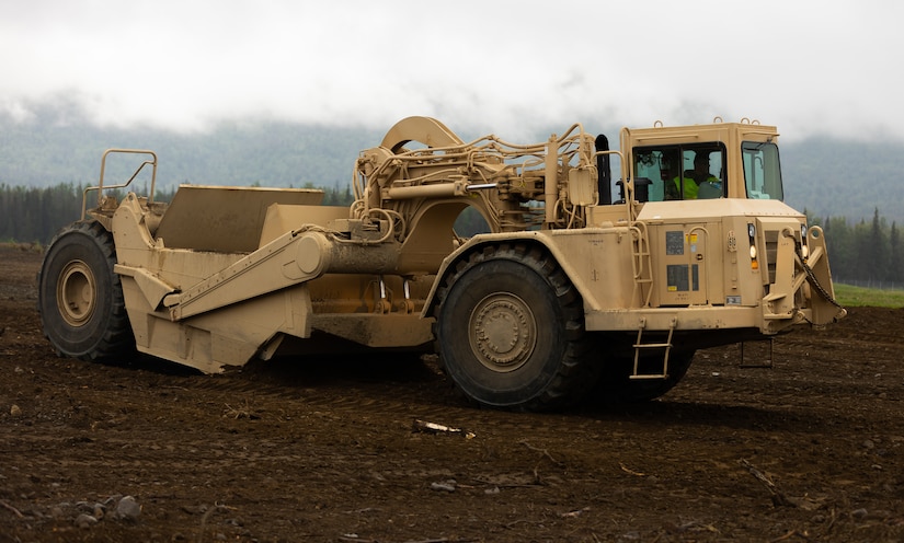 Alaska Army National Guard Sgt. Zachary Tomasetti, a horizontal construction engineer assigned to the 910th Engineer Support Company, operates a wheeled tractor-scraper to transport dirt to different land posts that will later be surveyed as a part of annual training on Joint Base Elmendorf-Richardson, Alaska, Aug. 8, 2023.