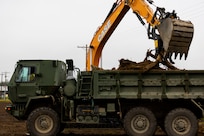 Alaska Army National Guardsmen, assigned to the 910th Engineer Support Company, assist one another by operating heavy machinery to dispose of any waste found at their construction site as a part of their annual training on Joint Base Elmendorf-Richardson, Alaska, Aug. 8, 2023.