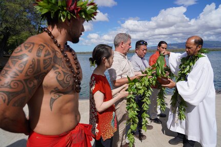 Kahu Kordell Kekoa, right, a Hawaiian priest, dips tea leaves in a koa bowl containing water to bless the maile lei held by participants, left, in a traditional Hawaiian blessing ceremony held at the water front of Pearl Harbor.