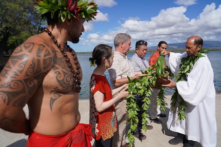 Kahu Kordell Kekoa, right, a Hawaiian priest, dips tea leaves in a koa bowl containing water to bless the maile lei held by participants, left, in a traditional Hawaiian blessing ceremony held at the water front of Pearl Harbor.