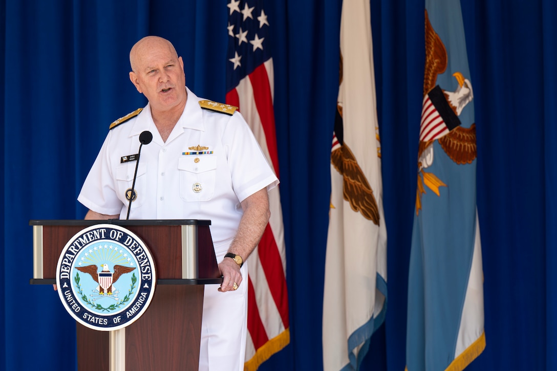 Vice Chairman of the Joint Chiefs of Staff Navy Adm. Christopher W. Grady speaks at a lectern with a group of flags in the background.