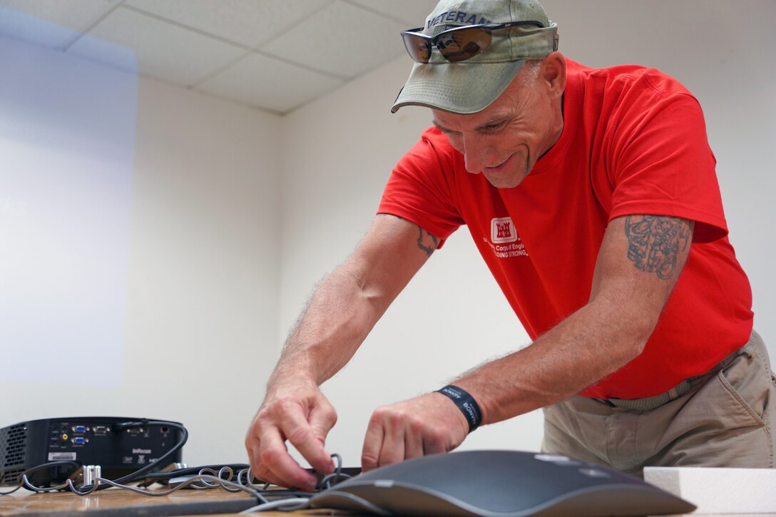 A man connects electronic devices that are sitting on a table