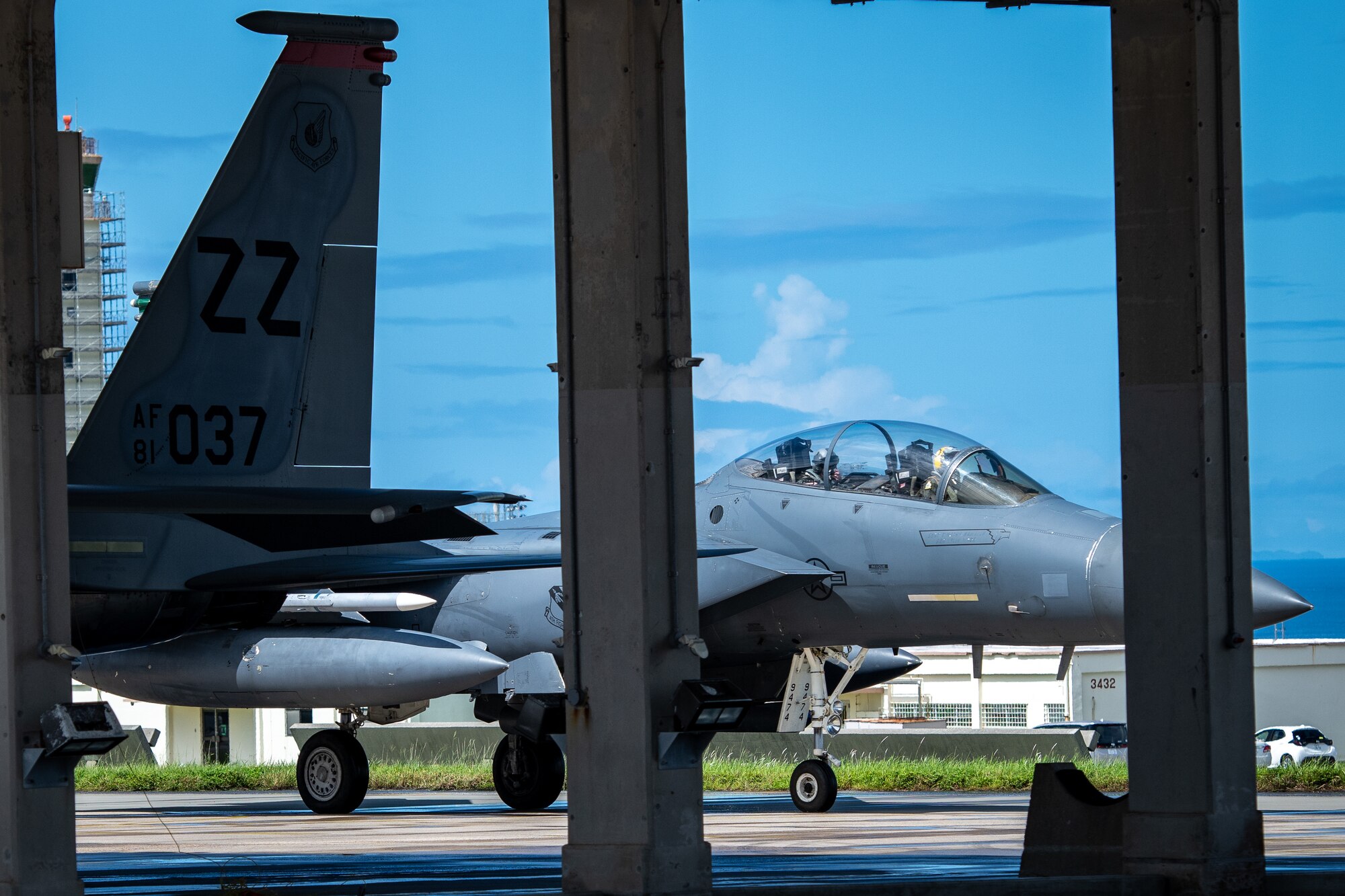 An F-15E taxis to the right on the other side of two concrete pillars