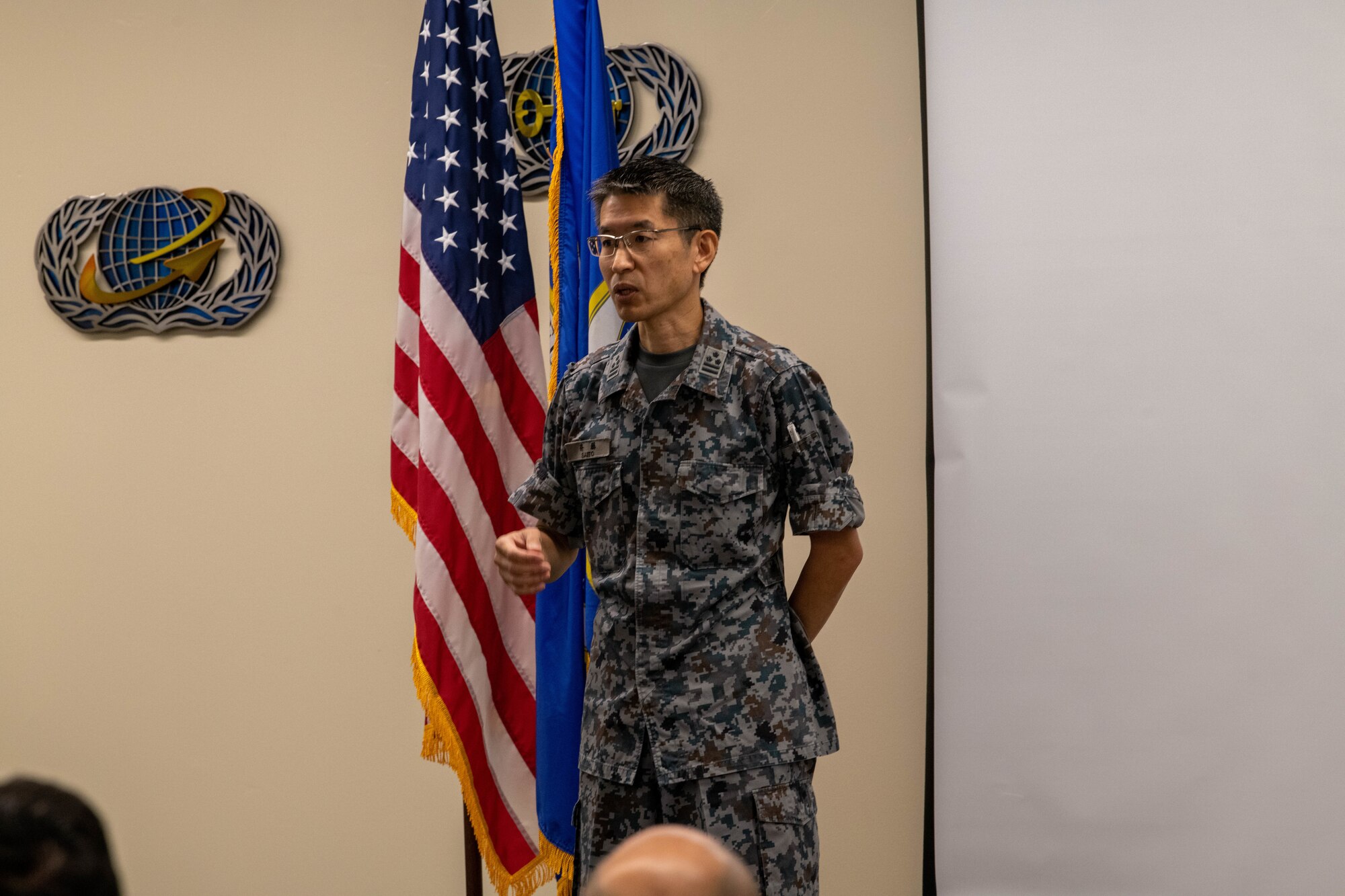 A Japanese military service member speaks to a crowd.