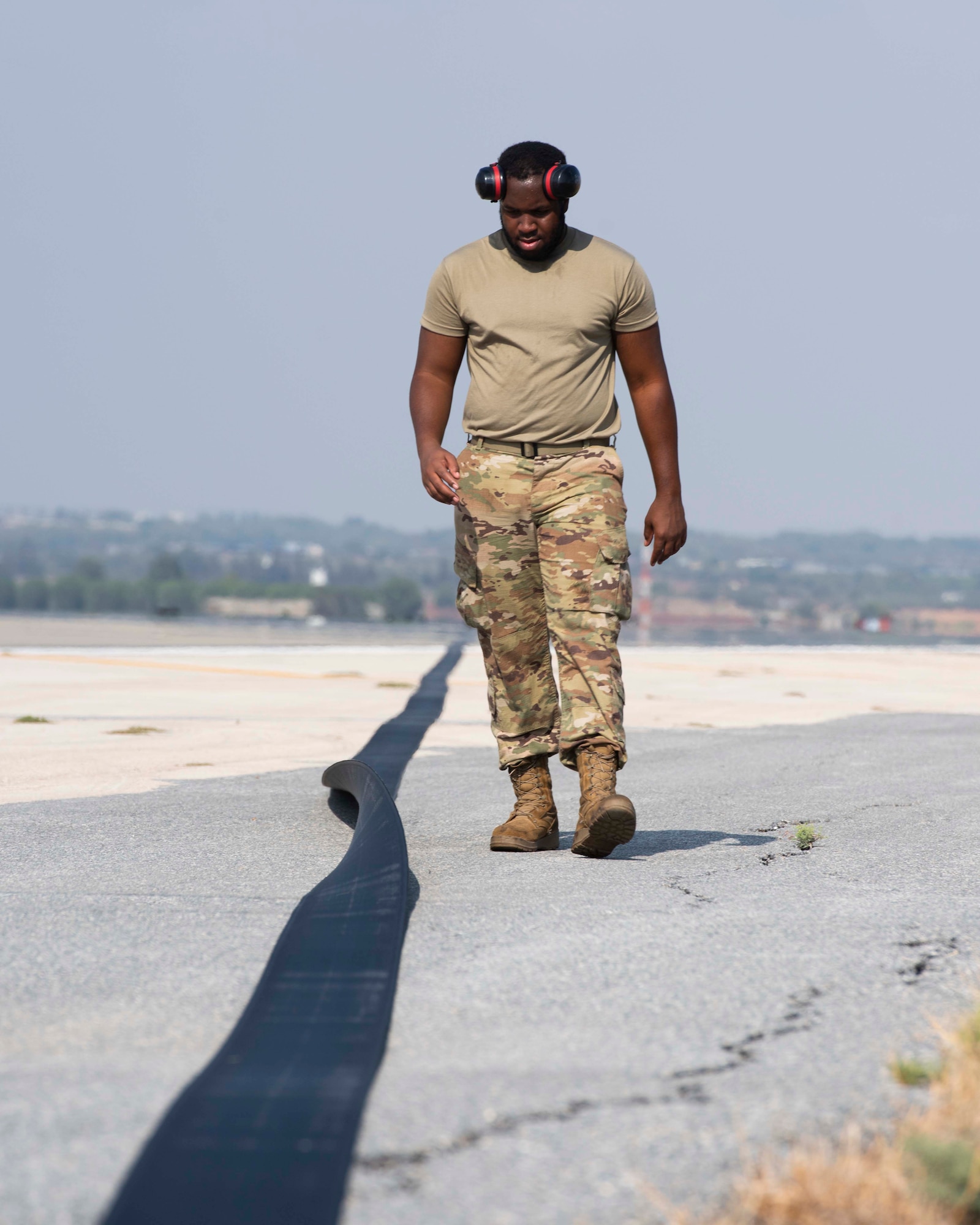 A man walks along an outstretched cable that stretches across a runway