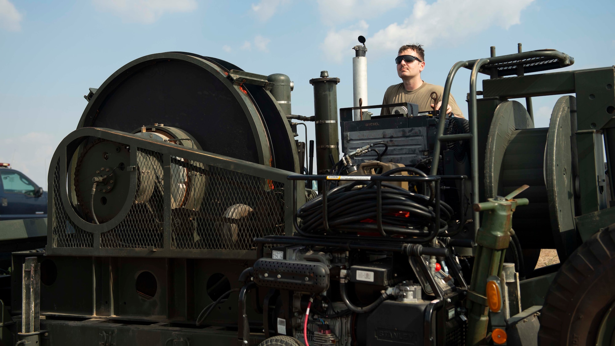 A man in sunglasses is perched atop a large piece of machinery.