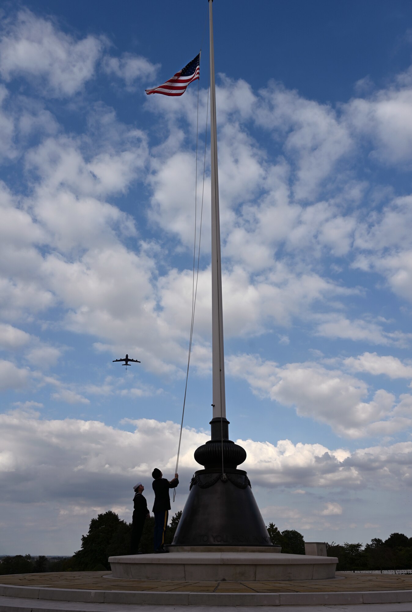 A KC-135 Stratotanker from the 100th Air Refueling wing prepares to perform a flyover as the Stars and Stripes flag is lowered at Madingley American Cemetery, Cambridgeshire, England, Sept. 15, 2023. There are 3,811 memorials and 5,127 names recorded on the Walls of the Missing, remembering and honoring those who sacrificed their lives for their country while serving overseas. (U.S. Air Force photo by Karen Abeyasekere)