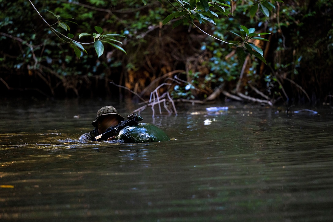 A Marine Raider with Marine Forces Special Operations Command traverses a river during a jungle mobility course, Aug. 4, 2023. Marine Raiders in the training program learned to maneuver in a jungle environment, conceal their movements, and track adversary movements. (U.S. Marine Corps photo by Cpl. Henry Rodriguez)