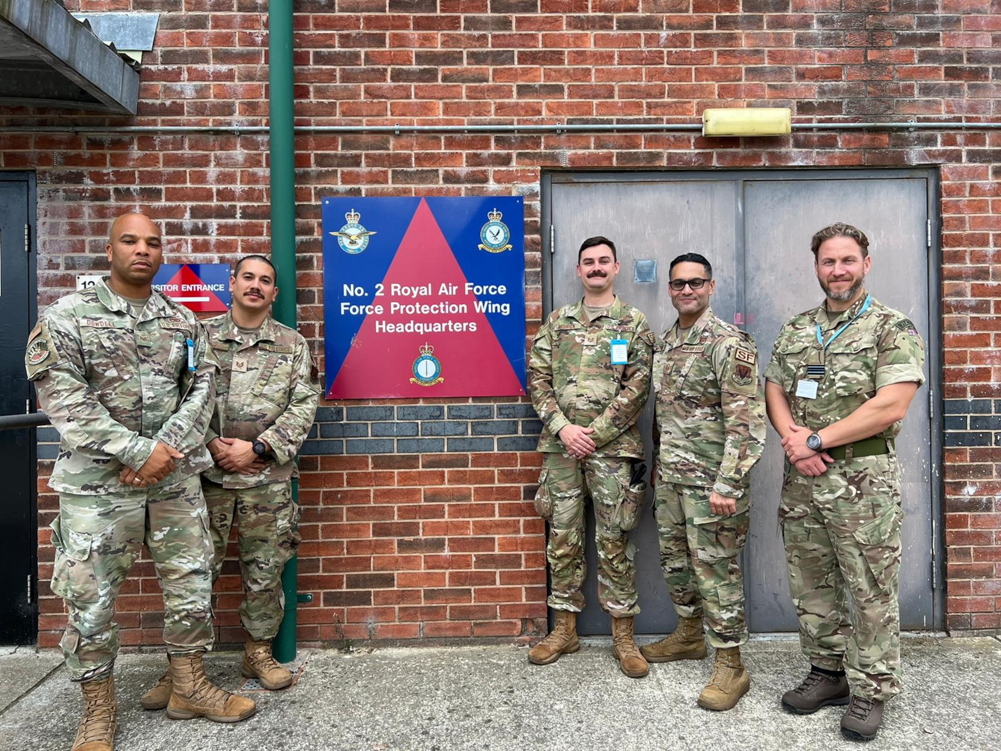 Four U.S. Air Force Airmen assigned to the 125th Security Forces Squadron along with host, Flight Lt. David Haslewood, 609 (West Riding) Squadron, RAF Regiment, are pictured before the No. 2 RAF Force Protection Wing headquarters building, Sept. 11, 2023. The Airmen are participating in the Military Reserve Exchange Program (MREP), a DoD initiative that allows for Reserve and Guard forces to partner with associated units to exchange knowledge, share tactics and procedures, and understand the training, doctrine and operations of NATO alliance partners. (U.S. Air National Guard photos by Tech Sgt. Chelsea Smith)