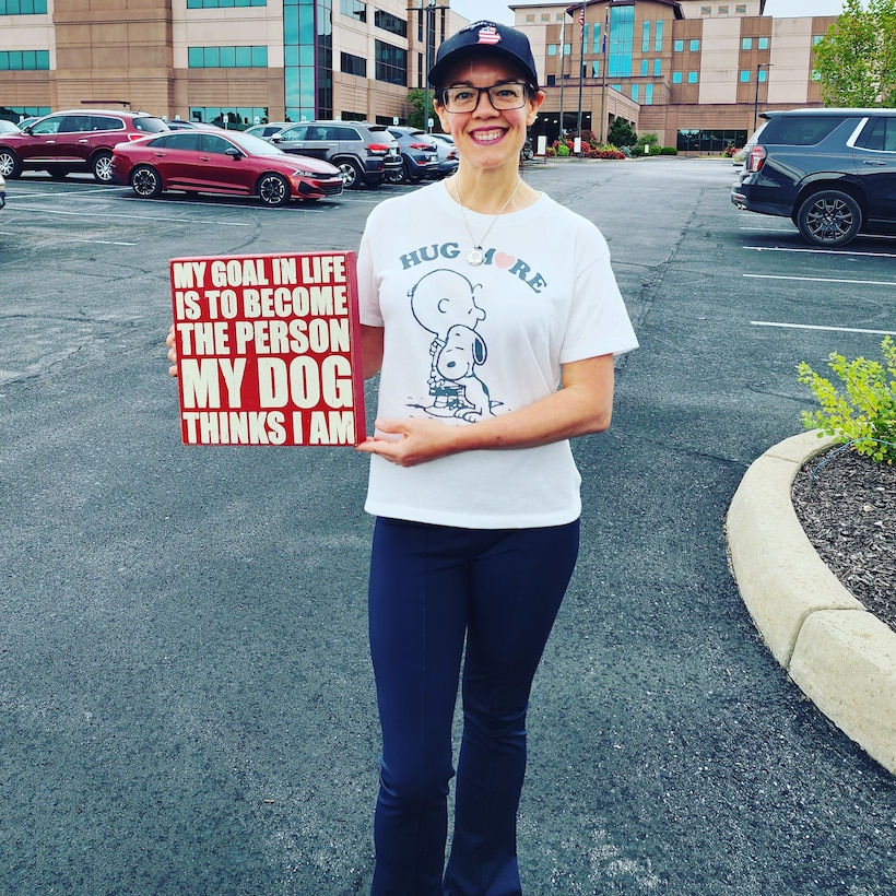 Woman holding a sign that reads My Goal In Life Is to Become The Person My Dog Thinks I Am.