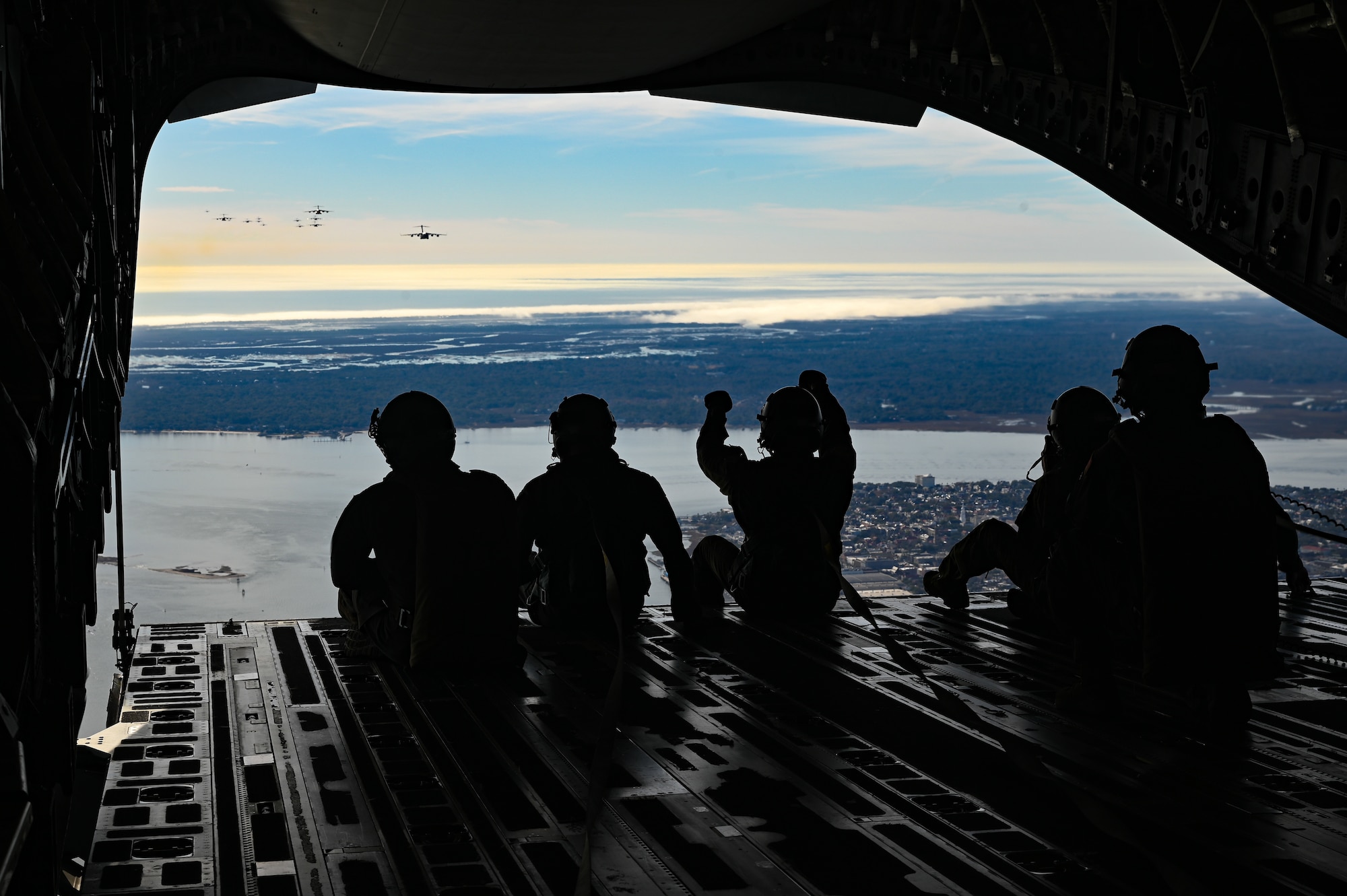 A silhouette of airmen direction other planes in the air.
