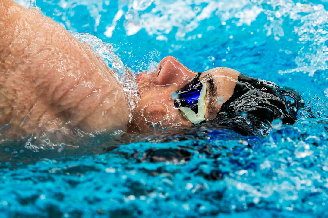 A close-up of a cadet performing the backstroke in a pool.