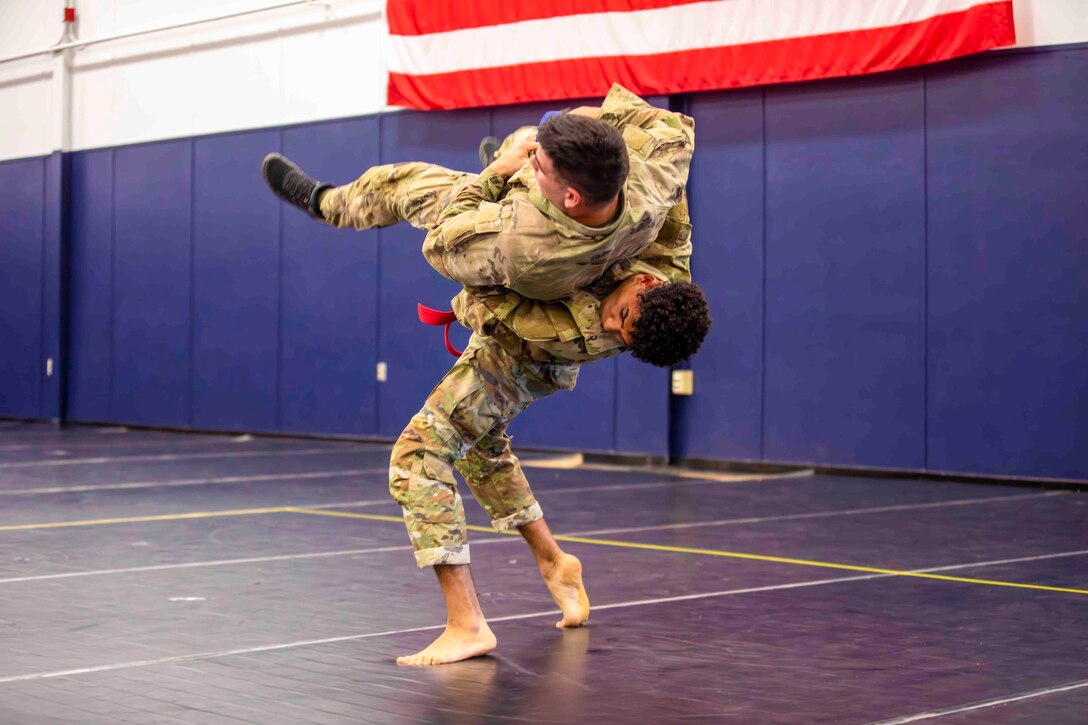 Two guardsmen grapple on wrestling mats.