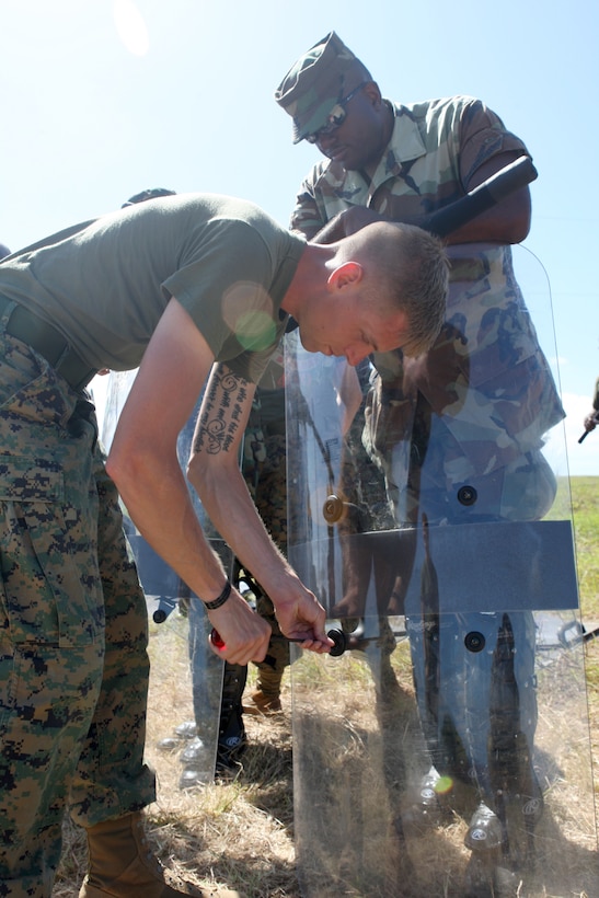 U.S. Marine Sgt. Andrew Notbohm, a military policeman from Military Police Company B, Headquarters and Service Battalion, 4th Marine Logistics Group, and a Moon Township, Pa. native, shares tightens screws of riot shields during a crowd control practice at Barbados Defence Force Base Paragon, Christ Church, Barbados, June 18, 2012, for Exercise Tradewinds 2012. Tradewinds is a multinational, interagency exercise designed to develop and sustain relationships that improve the capacity of U.S., Canadian and 15 Caribbean partner nations security forces to counter transnational crime and provide humanitarian assistance and disaster relief.