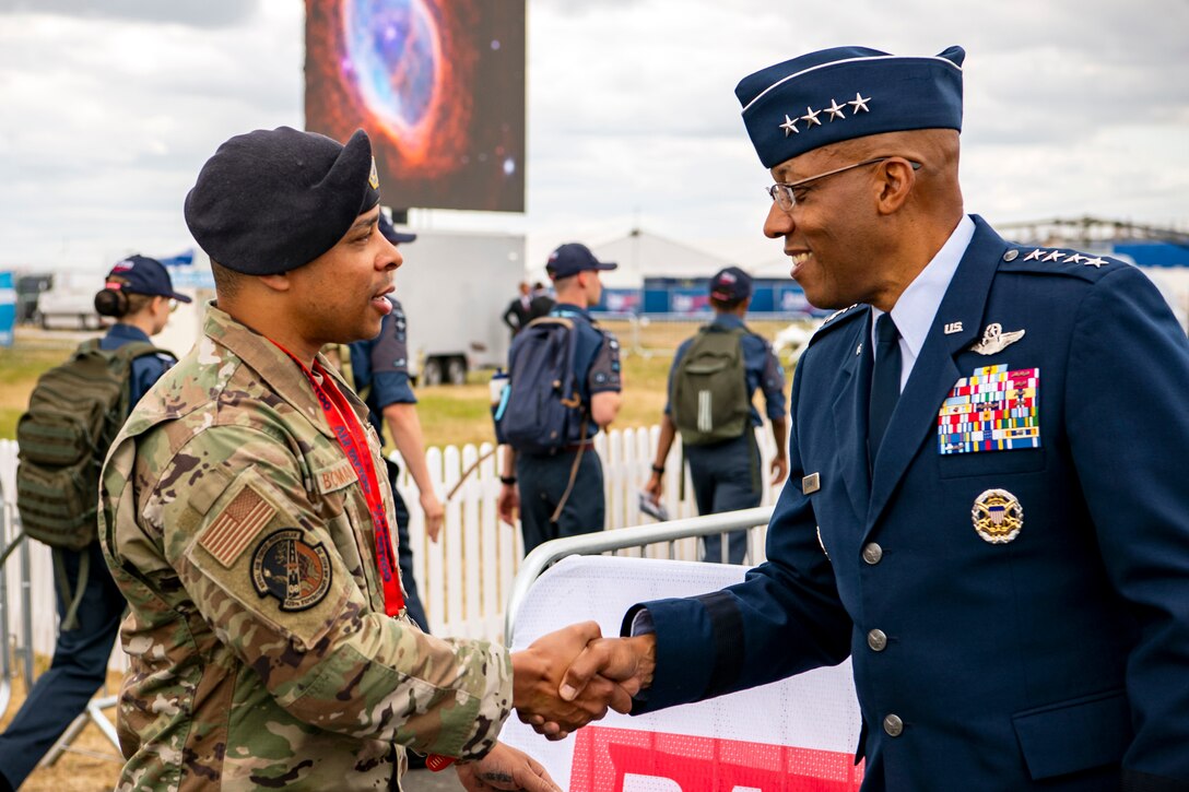 An Air Force general shakes hands with an airman at an outdoor event.