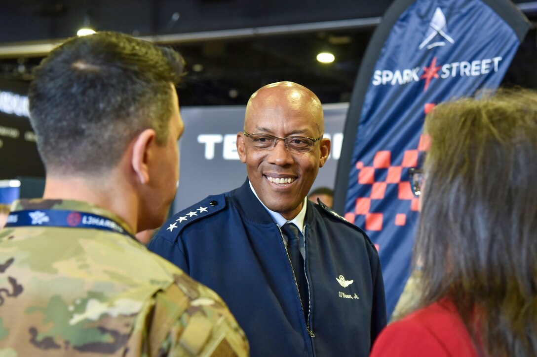 An Air Force general talks to a service member and a civilian in an exhibition space.