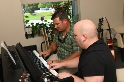 Marine Corps Gunnery Sergeant Paul "Buck" Chambers (left) works with Intrepid Spirit's Music Therapist Clayton Cooke during a music therapy session.