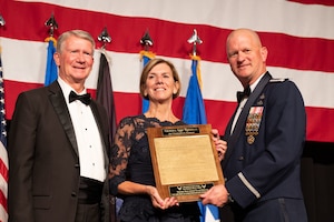 U.S. Air Force Col. Joshua DeMotts, right, the 99th Air Base Wing commander, presents a plaque to retired U.S. Air Force Gen. Lori Robinson, center, the former commander of United States Northern Command, as her husband retired U.S. Air Force Maj. Gen. David Robinson, former mobilization assistant to the Chief of the Air Force Reserve, Headquarters U.S. Air Force, stands by in Las Vegas, Nevada, Sept. 16, 2023.