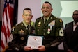 Two Army Soldiers pose for a photo holding an written citation award.