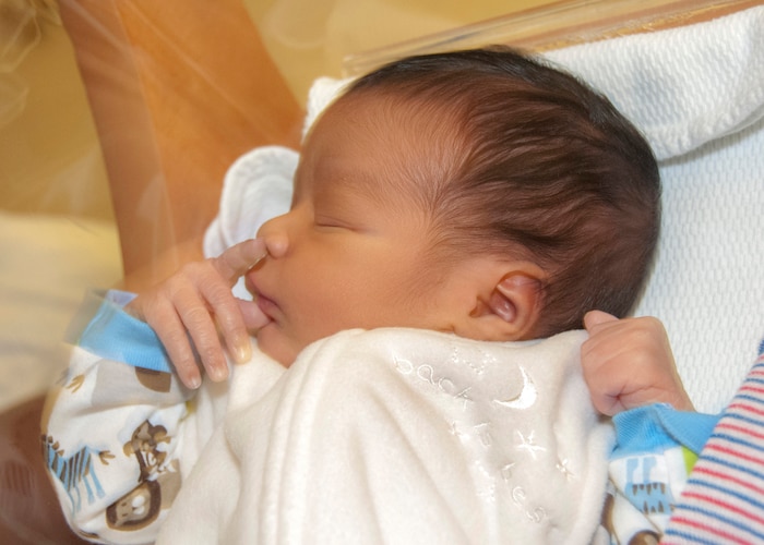 A baby sleeps in a zipped up blanket.