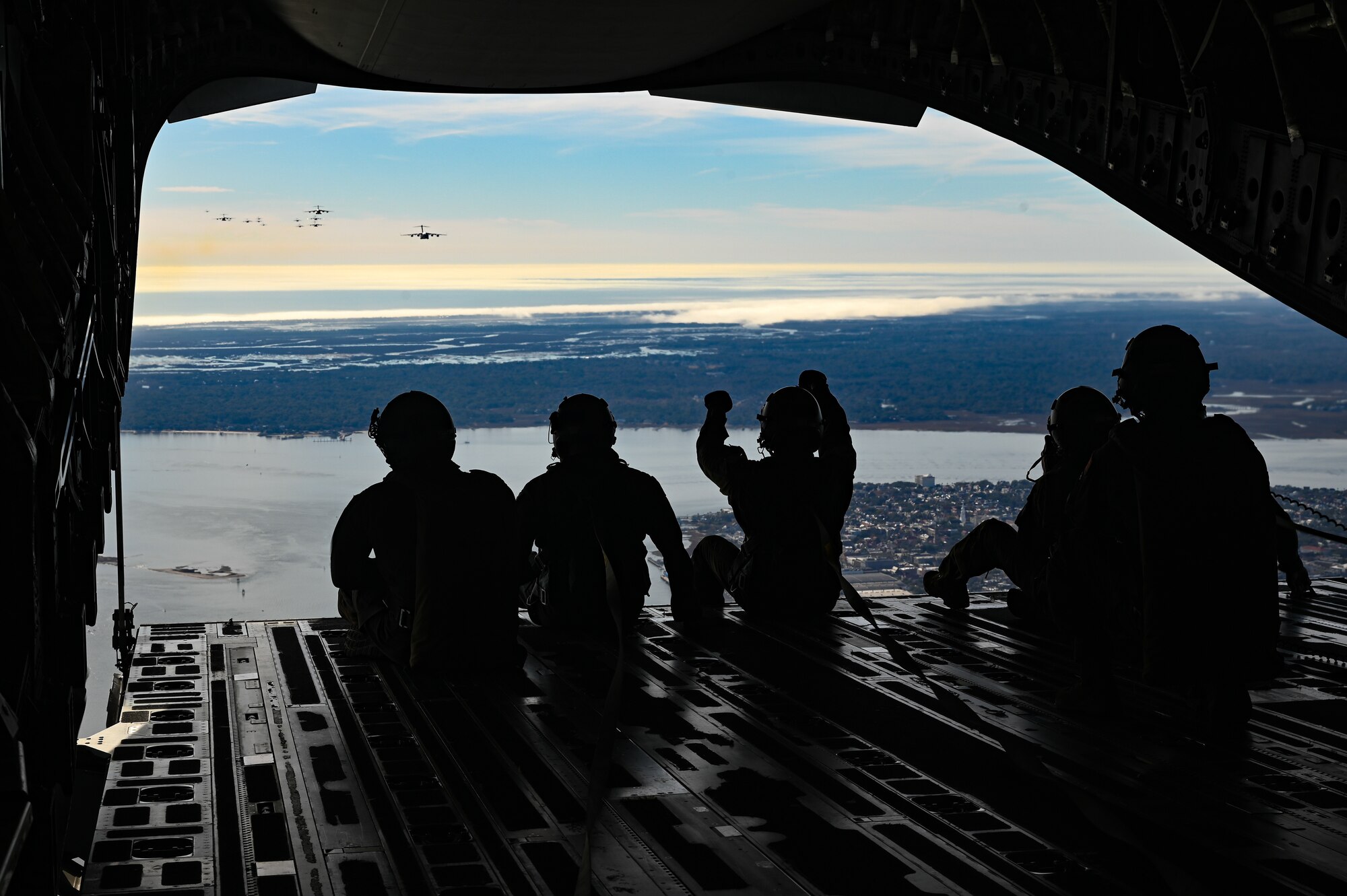 A silhouette of airmen direction other planes in the air.