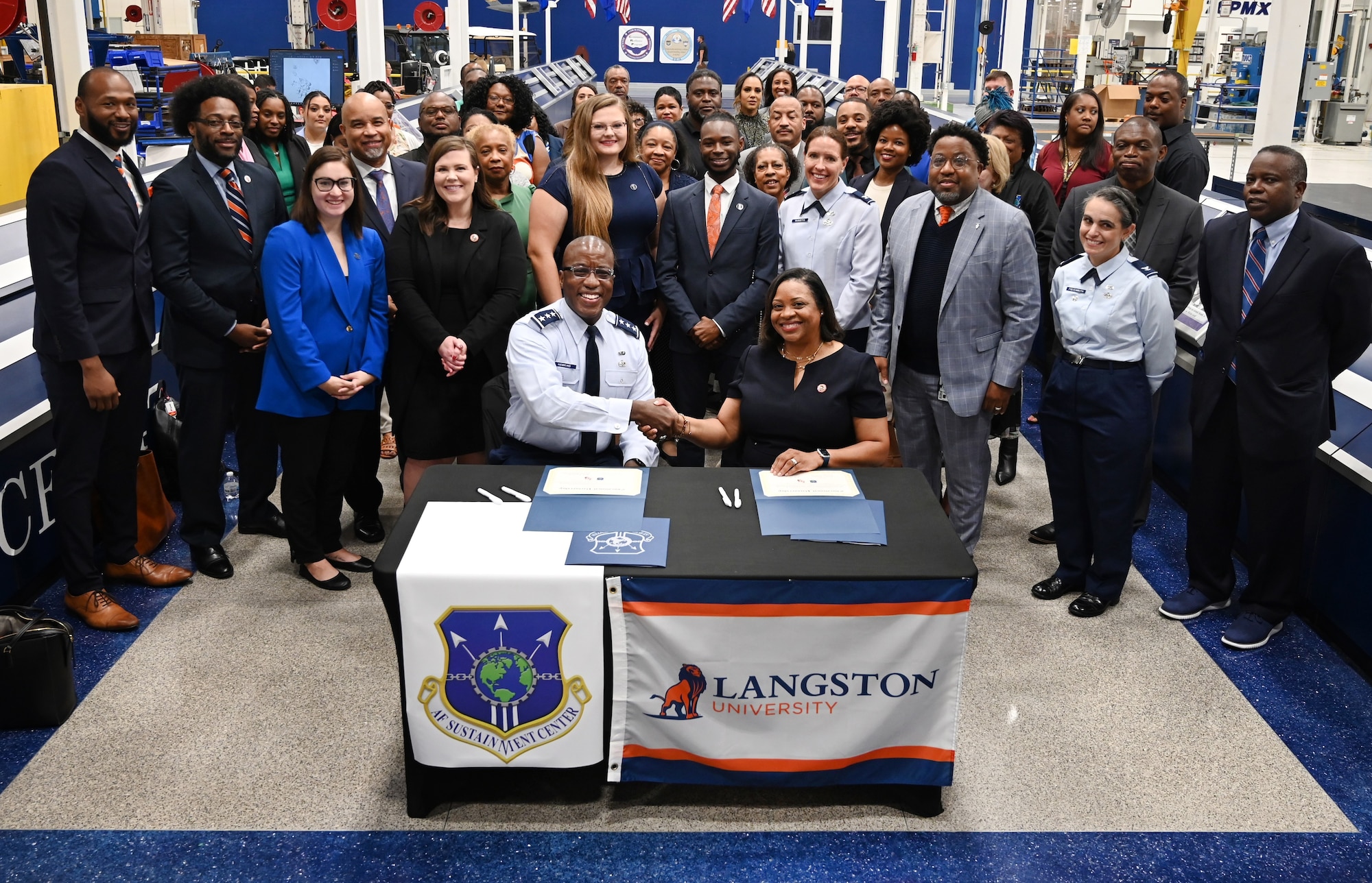 Surrounded by Langston alumni employed at Tinker Air Force Base, Okla., and Air Force Sustainment Center and LU leadership, U.S. Air Force Lt. Gen. Stacey T. Hawkins, AFSC commander, and Dr. Ruth Ray Jackson, Langston University interim president shake hands after the signing of official documents establishing an educational partnership agreement between the two entities.