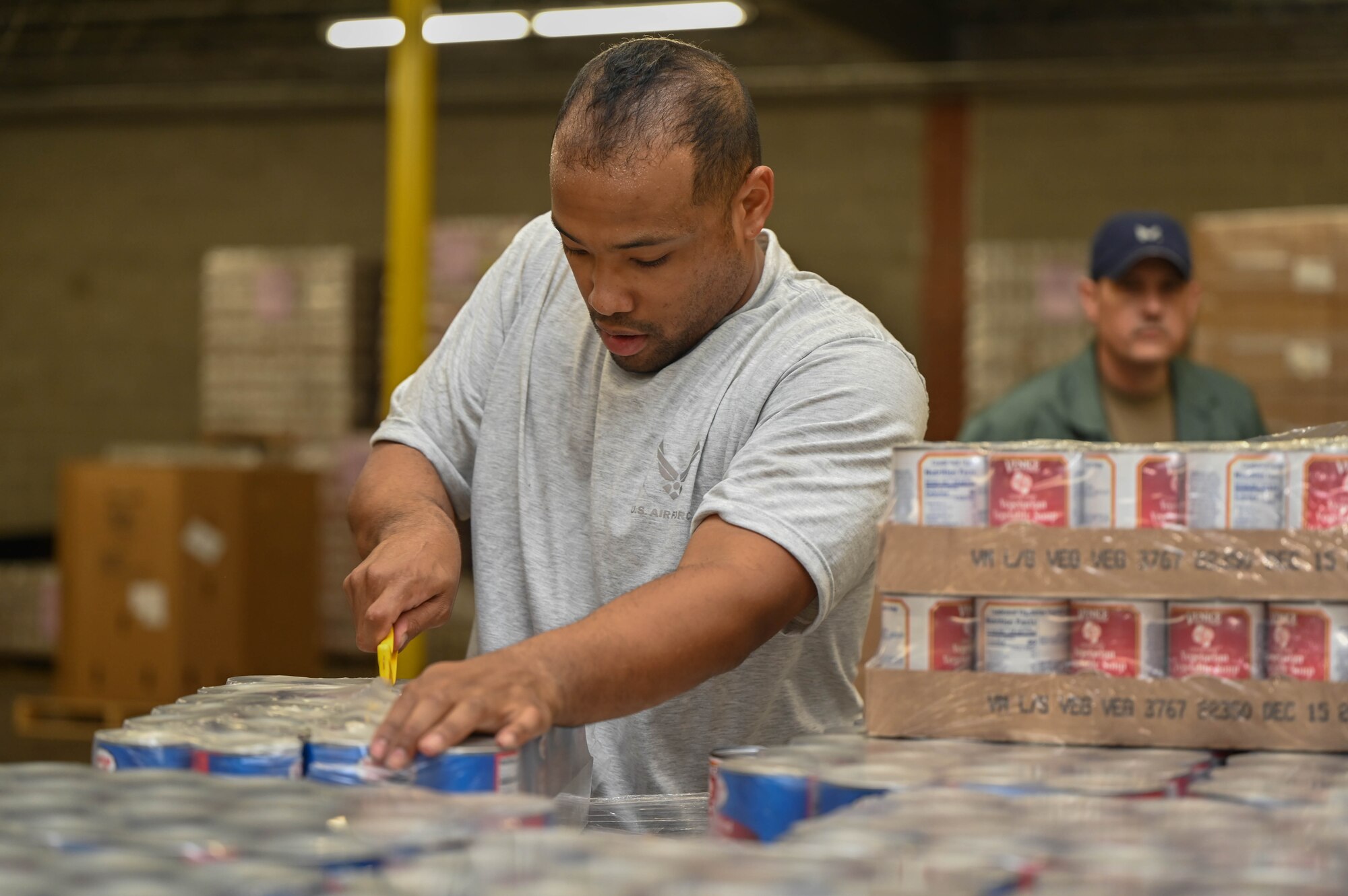 a man opens a case of canned goods