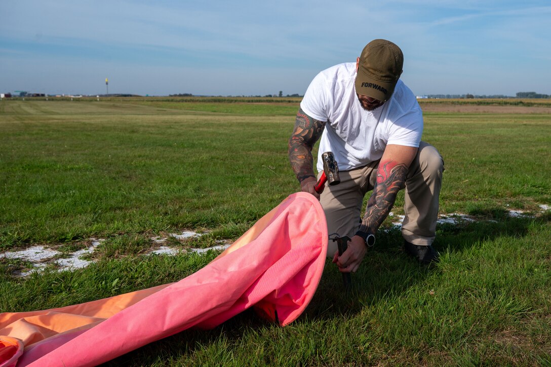 An airmen secures an airstrip marker while setting up a landing zone.