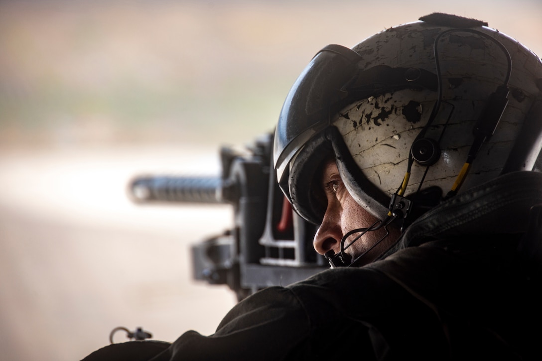 A Marine sits behind a machine gun.