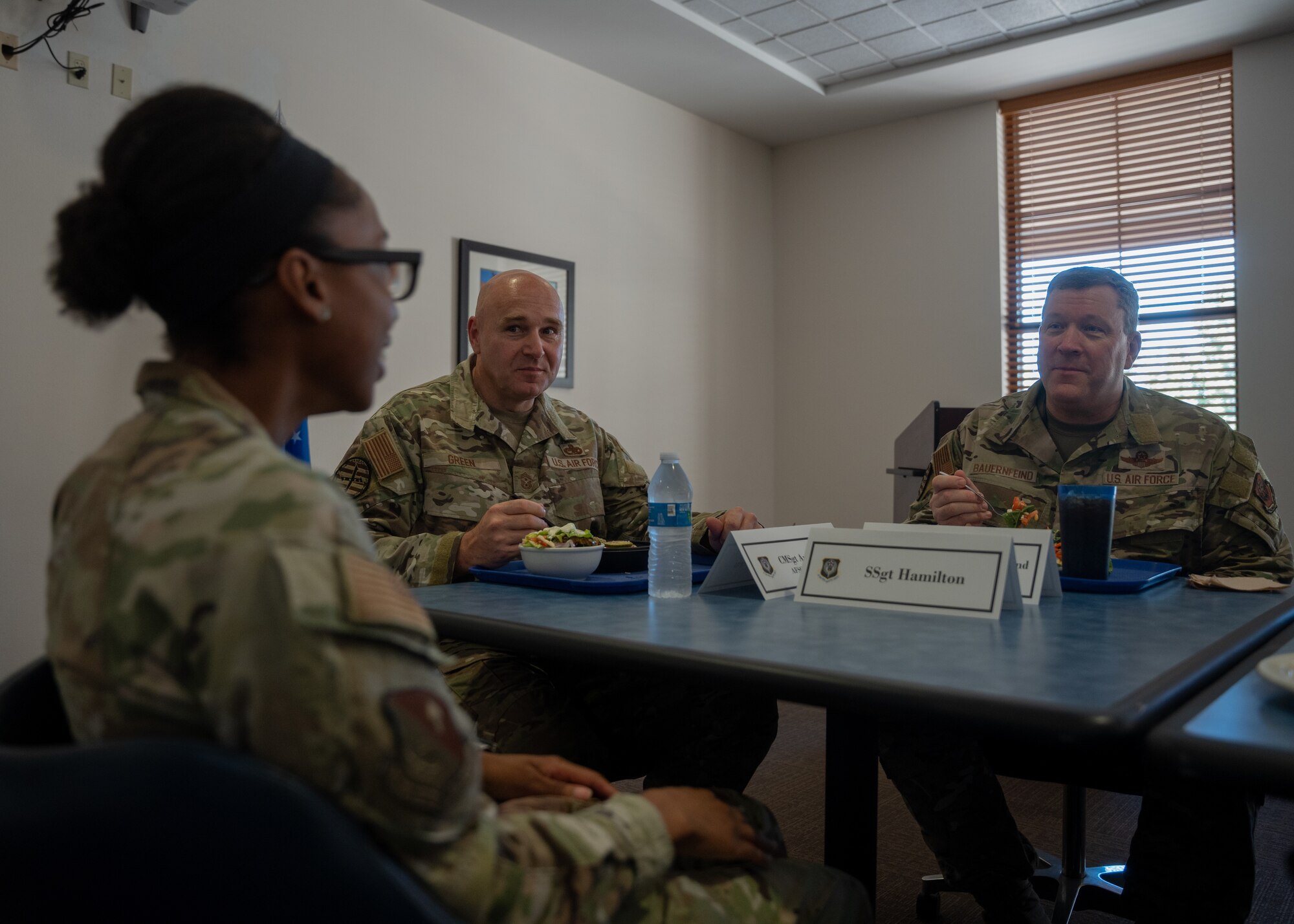 Three service members sit at a table in the dining facility discussing medical challenges at Cannon Air Force Base.