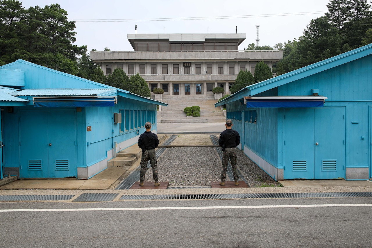 Members of foreign military stand next to buildings.