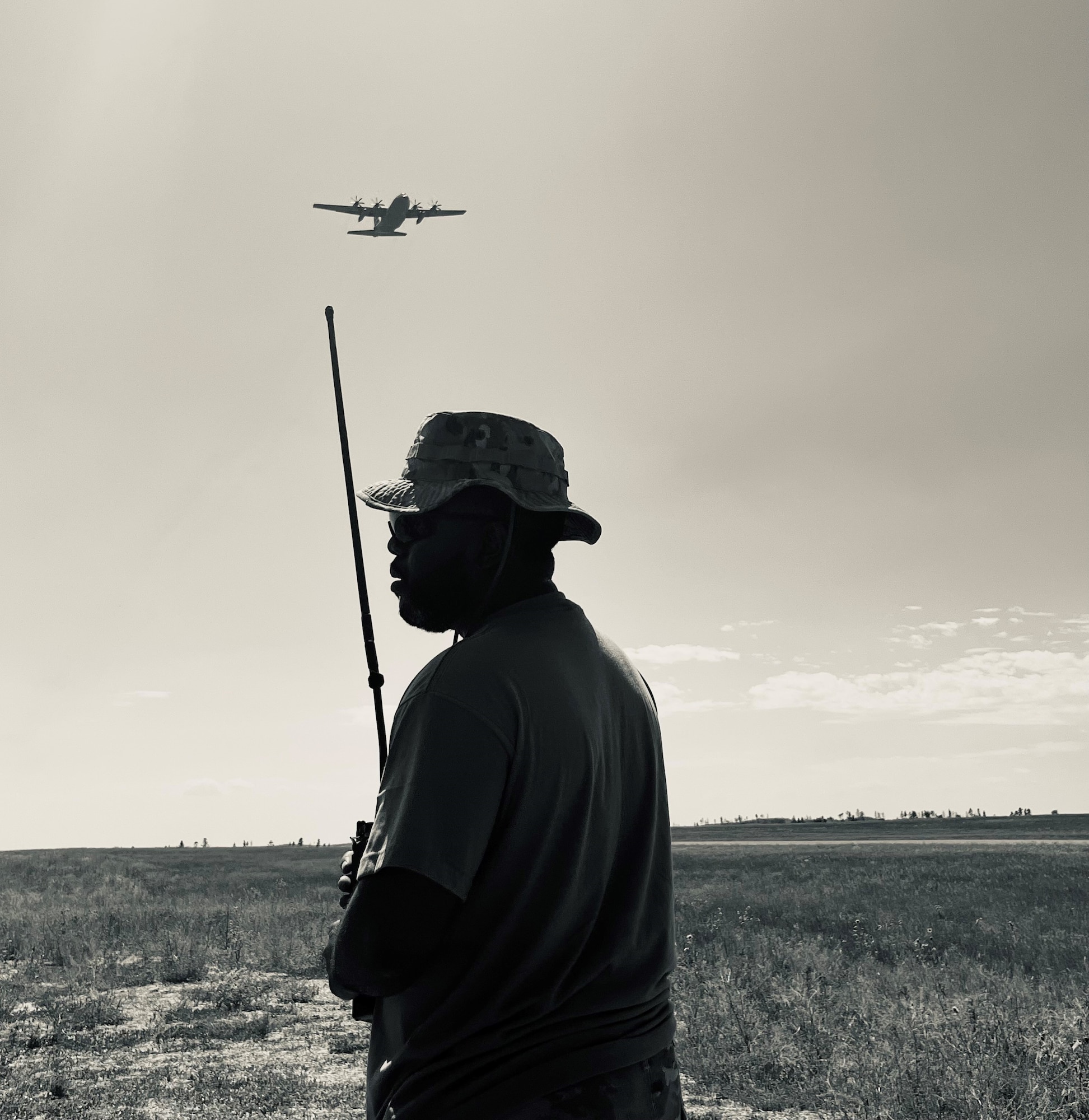A man holding a radio stands below an aircraft.