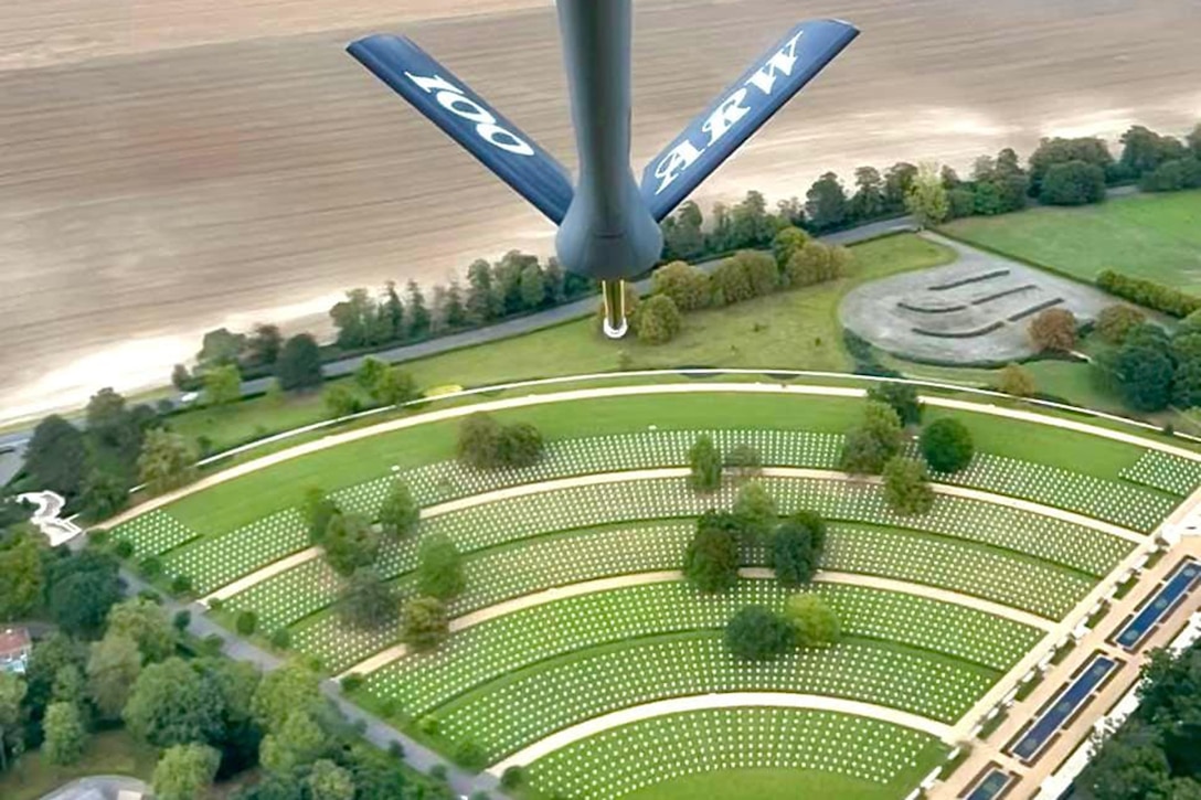 A military aircraft flies over a cemetery.