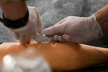 An Airman from the 341st Medical Group simulates the administration of intravenous fluids into a mannequin arm during Ready EAGLE II, a training exercise held biennially at Malmstrom Air Force Base, Mont., Sept. 21, 2023. Ready EAGLE II is a medical readiness contract providing training and exercise for the squadron on a biennial basis. (U.S. Air Force photo by Senior Airman Breanna Christopher Volkmar)