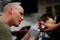 An Airman from the 341st Medical Group applies moulage to a finger in preparation for Ready EAGLE II at Malmstrom Air Force Base, Mont., Sept. 21, 2023. Moulage is the art of applying mock injuries for the purpose of training medical and military personnel. (U.S. Air Force photo by Senior Airman Breanna Christopher Volkmar)