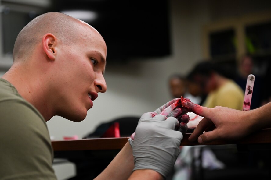 An Airman from the 341st Medical Group applies moulage to a finger in preparation for Ready EAGLE II at Malmstrom Air Force Base, Mont., Sept. 21, 2023. Moulage is the art of applying mock injuries for the purpose of training medical and military personnel. (U.S. Air Force photo by Senior Airman Breanna Christopher Volkmar)