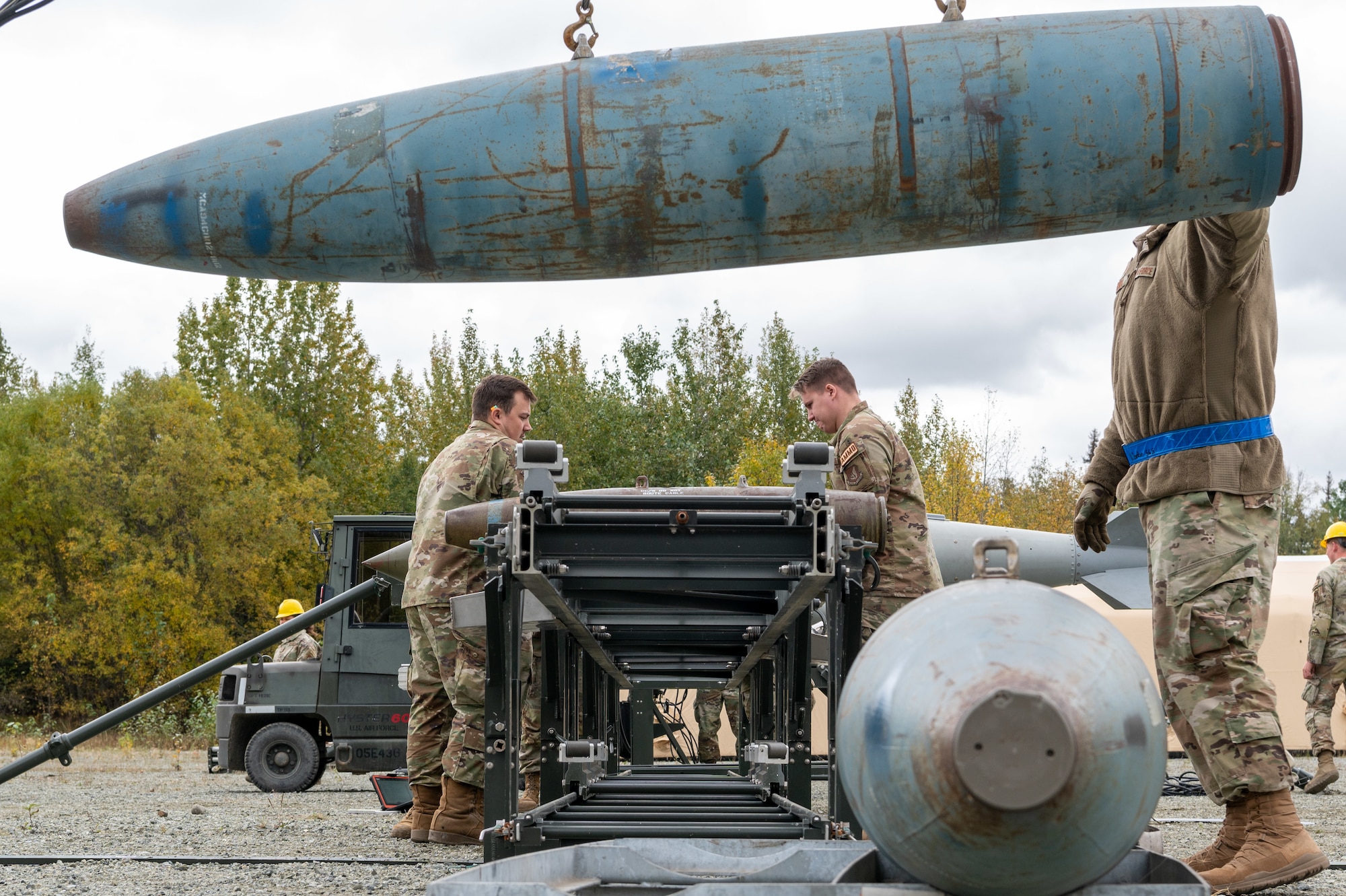 U.S. Air Force Senior Airman Justin Sikes (left) and Senior Airman Willis Collier (middle), Airmen assigned to the 3rd Munitions Squadron, work on dummy ordnance while Tech. Sgt. Kyle Gordon loads dummy ordnance onto the line during the second annual Nimble Flurry exercise at Joint Base Elmendorf-Richardson, Alaska, Sept 18, 2023.