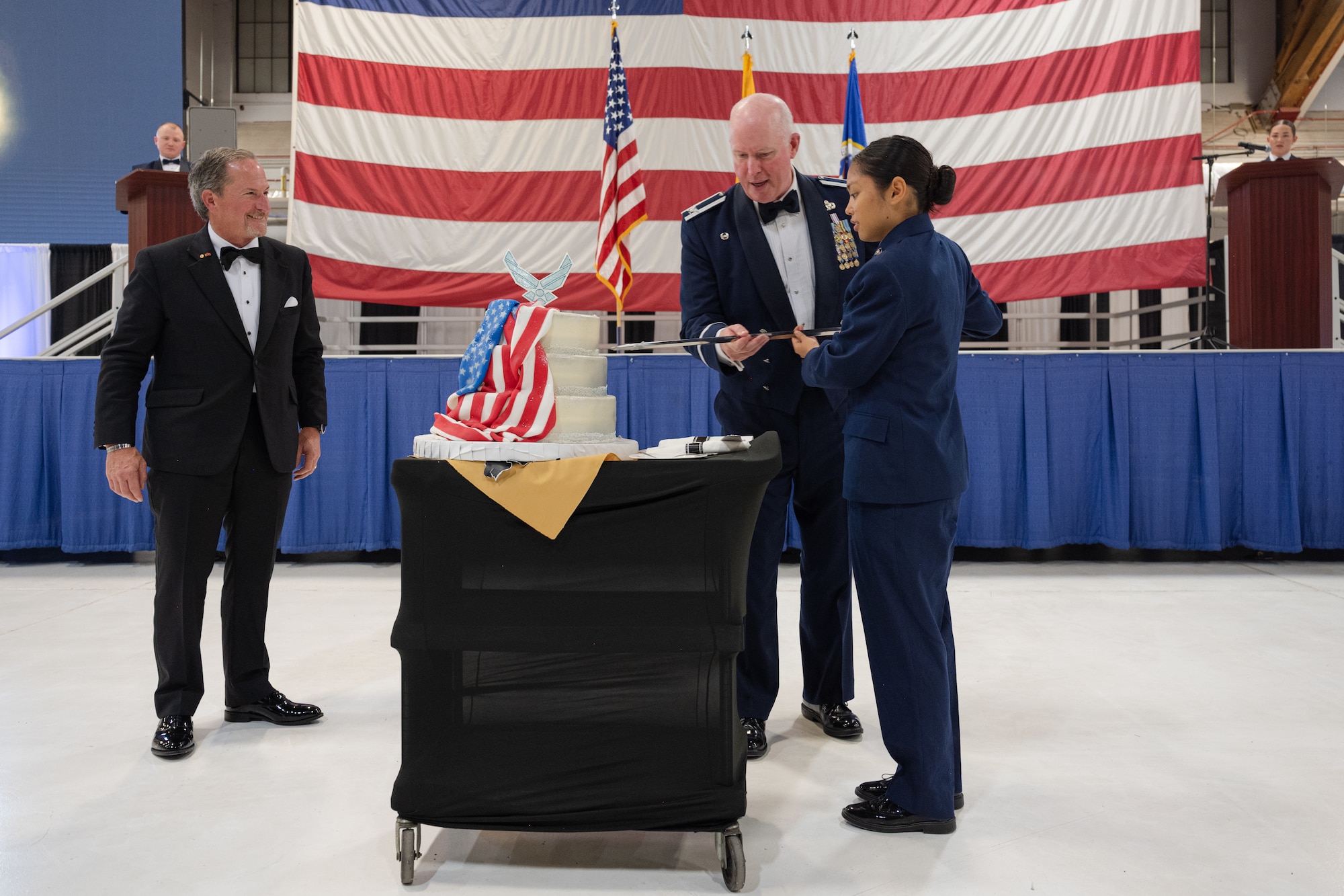Retired U.S. Air Force Gen. David L. Goldfein, left, watches as U.S. Air Force Col. Kevin Campbell, 49th Mission Support Group commander, middle, and Airman Basic Sherynne Elgin, 49th Logistics Readiness Squadron aircraft parts store apprentice, cut the cake during the 2023 Holloman Air Force Ball at Holloman Air Force Base, New Mexico, Sept. 23, 2023. It is customary for the most senior and junior Airmen to cut the cake which represents the heritage between generations. (U.S. Air Force photo by Senior Airman Antonio Salfran)