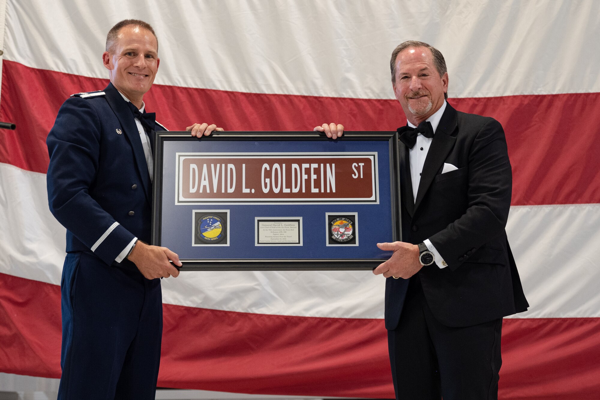 Retired U.S. Air Force Gen. David L. Goldfein, right, receives a gift from U.S. Air Force Col. Justin Spears, 49th Wing commander, during the 2023 Holloman Air Force Ball at Holloman Air Force Base, Sept. 23, 2023. In June of 2006, Goldfein assumed command of the 49th Fighter Wing, which members of the current 49th Wing have decided to commemorate by having him attend the ball as our keynote speaker and naming a street in his honor. (U.S. Air Force photo by Senior Airman Antonio Salfran)