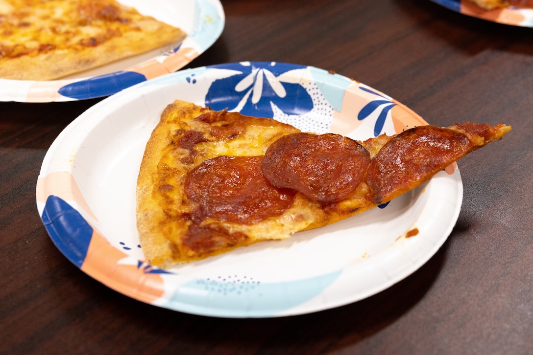 U.S. Marines with Marine Wing Support Squadron 172, 1st Marine Aircraft Wing, eat pizza provided by USO Foster on Camp Foster, Okinawa, Japan, Aug. 11, 2023. Typhoon Khanun moved through Okinawa as a category 4 storm, bringing strong winds, heavy rain and high seas, marking one of the strongest storms to affect the island in recent years. USO Foster brought pizza for Marines in CLR-3 for assisting in the recovery phase after the typhoon. During the recovery phase of the typhoon, MWSS-172 assisted with providing essential supplies to military personnel and the disposal of debris on military installations. (U.S. Marine Corps photo by Cpl. Thomas Sheng)