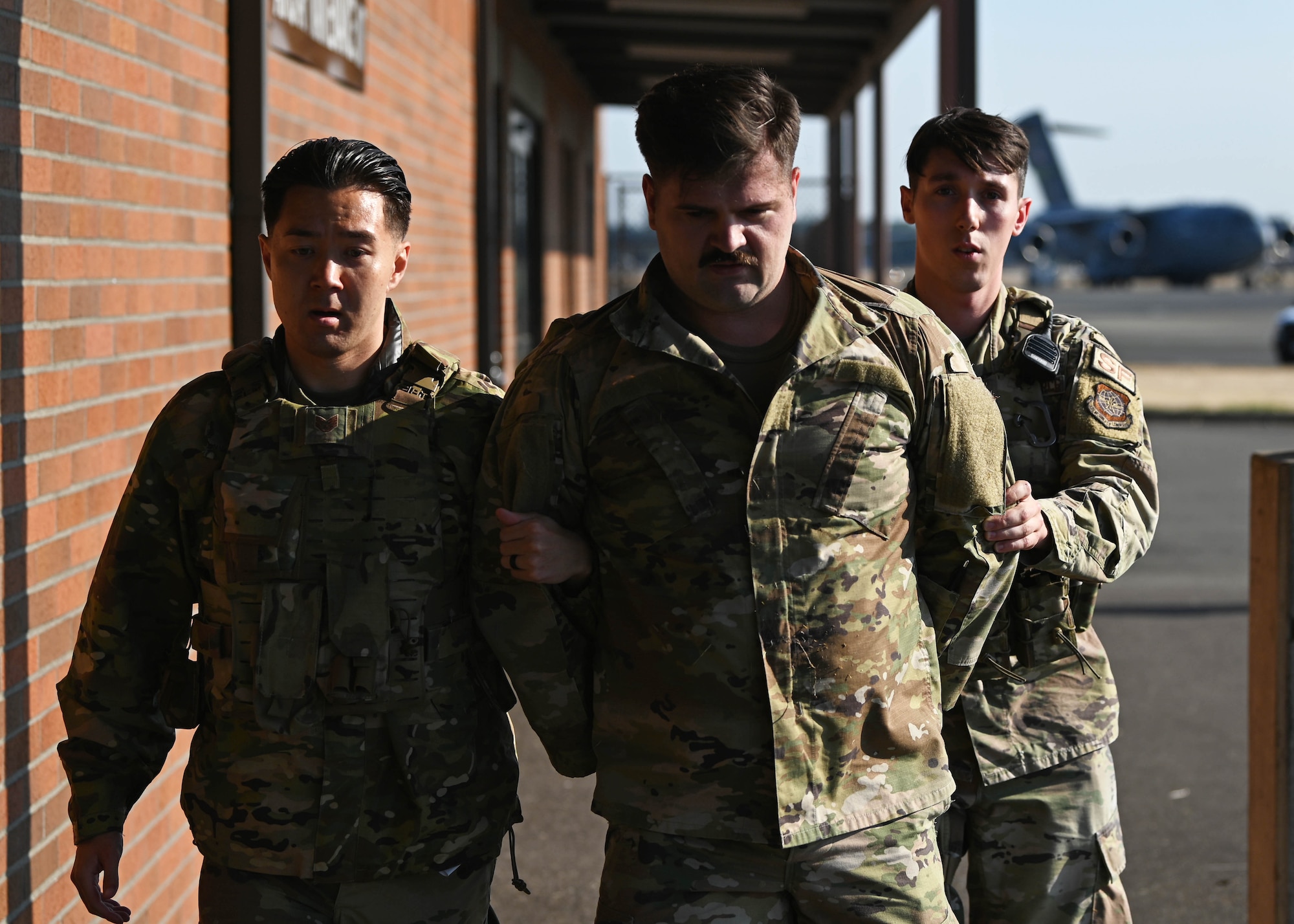 U.S. Air Force Staff Sgt. Justin Sagin, left, flight sergeant, and Senior Airman Logun Dienberg, right, response force member, both with the 627th Security Forces Squadron, apprehend a subject who simulated a flightline breach during Exercise Rainier War 23A at Joint Base Lewis-McChord, Washington, Sept. 22, 2023. Rainier War is an exercise led by the 62d Airlift Wing designed to evaluate the ability to generate, employ and sustain in-garrison and forward deployed forces, ensuring strategic advantage by advancing warfighting capabilities. (U.S. Air Force Senior Airman Callie Norton)