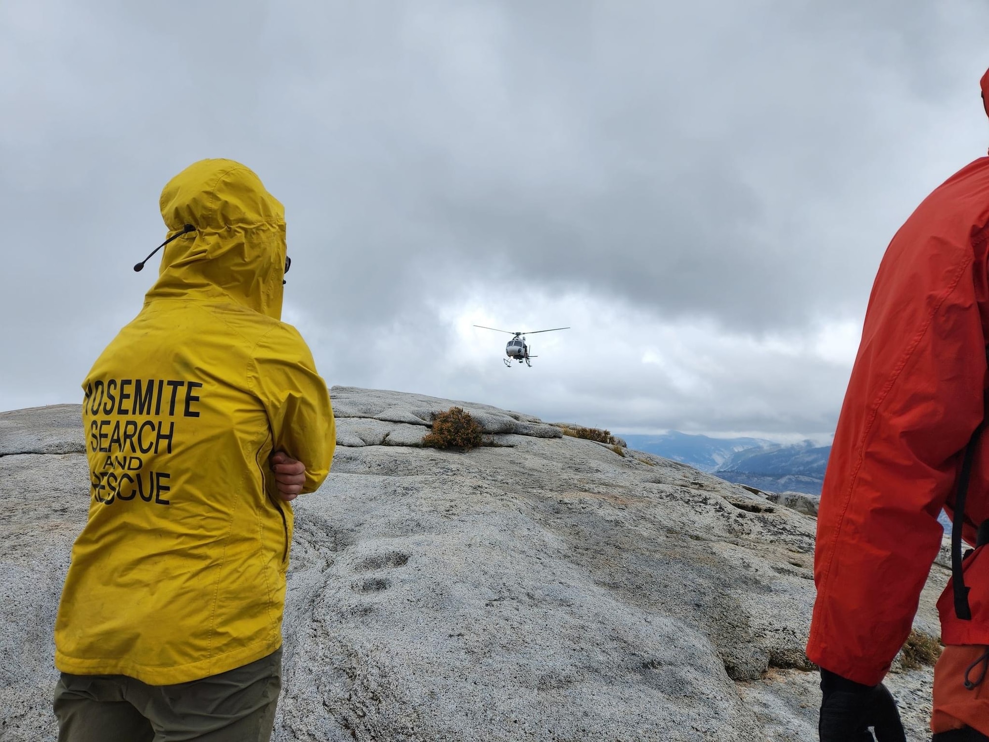 mountain climbers wait for a helicopter to land