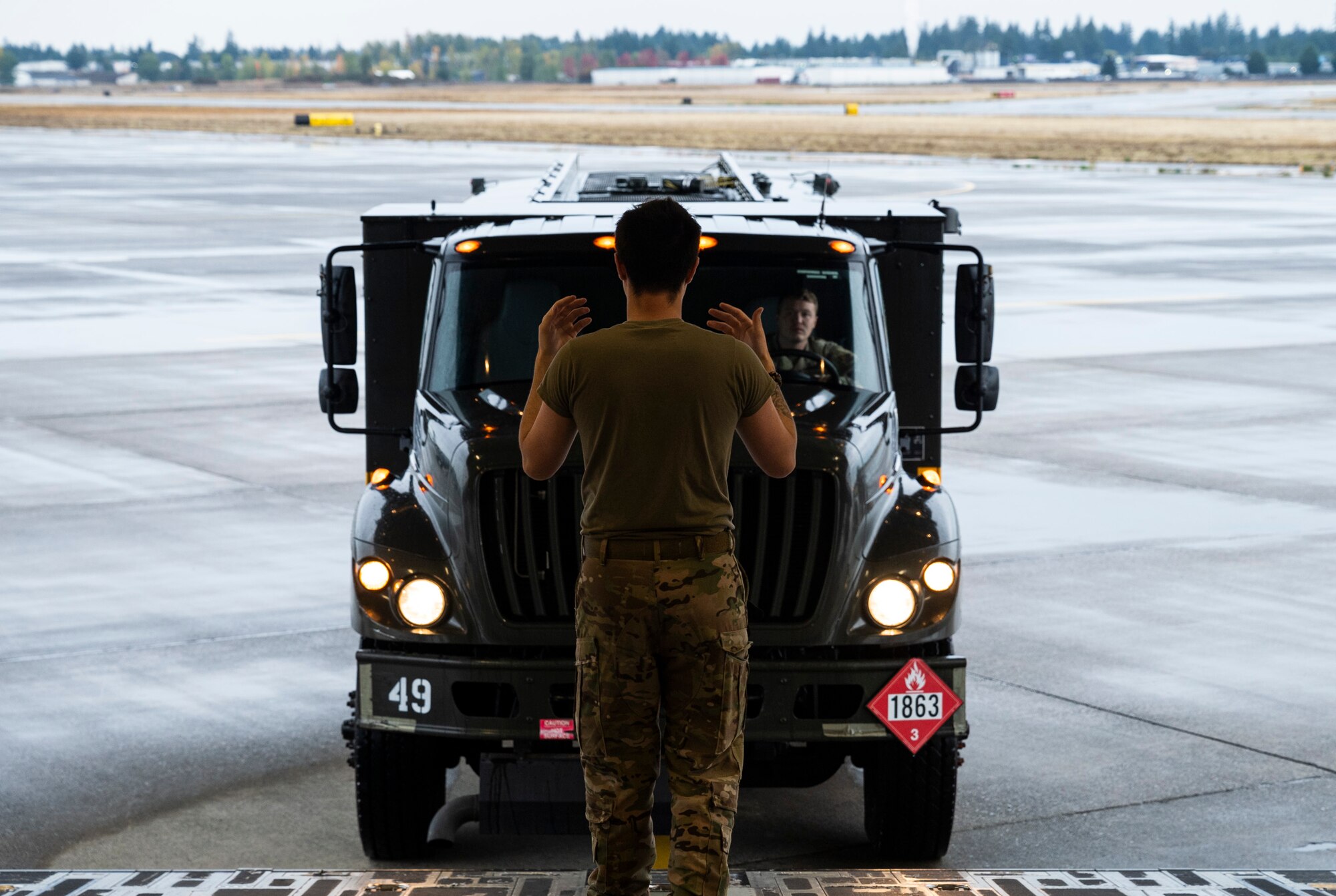 U.S. Air Force Senior Airman Kainoa Cook, a loadmaster with the 4th Airlift Squadron, marshals an R-11 fuel truck onto a C-17 Globemaster III during Exercise Rainier War 23A at Joint Base Lewis-McChord, Washington, Sept. 25, 2023. Rainier War is an annual exercise led by the 62d Airlift Wing designed to evaluate the ability to generate, employ and sustain in-garrison and forward deployed forces. These exercises are necessary in assessing and maintaining wartime operational tempos, ensuring command and control across multiple locations. During the exercise, Airmen will respond to scenarios that replicate today’s contingency operations and will address full-spectrum readiness against modern threats brought on by peer adversaries. (U.S. Air Force photo by Staff Sgt. Rachel Williams)