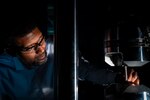 A man places a metal piece onto a machine.