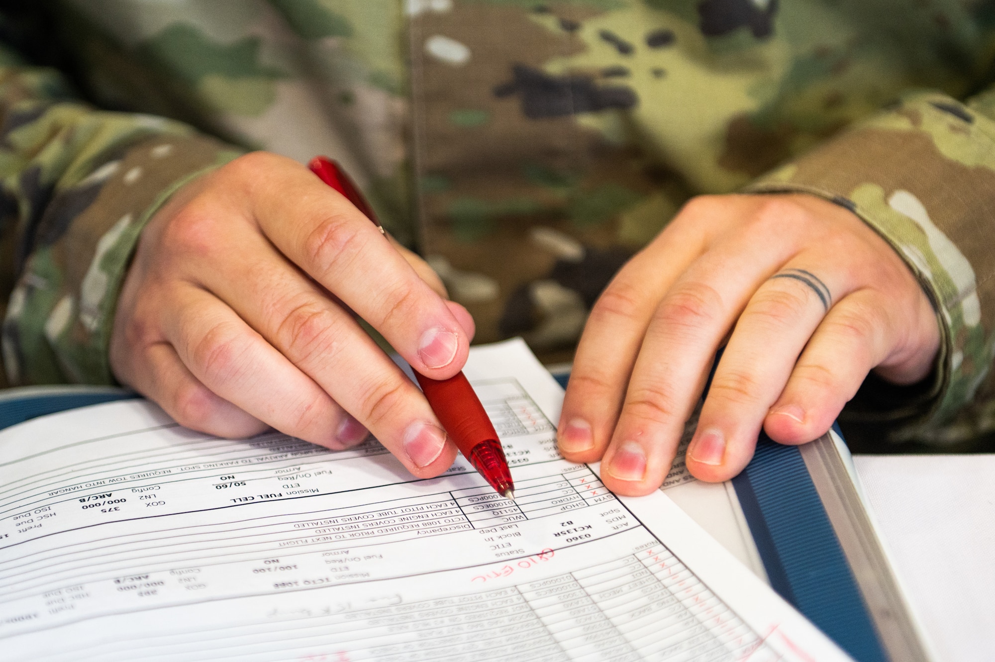 Close-up of an Airman's hands as he fills out a form