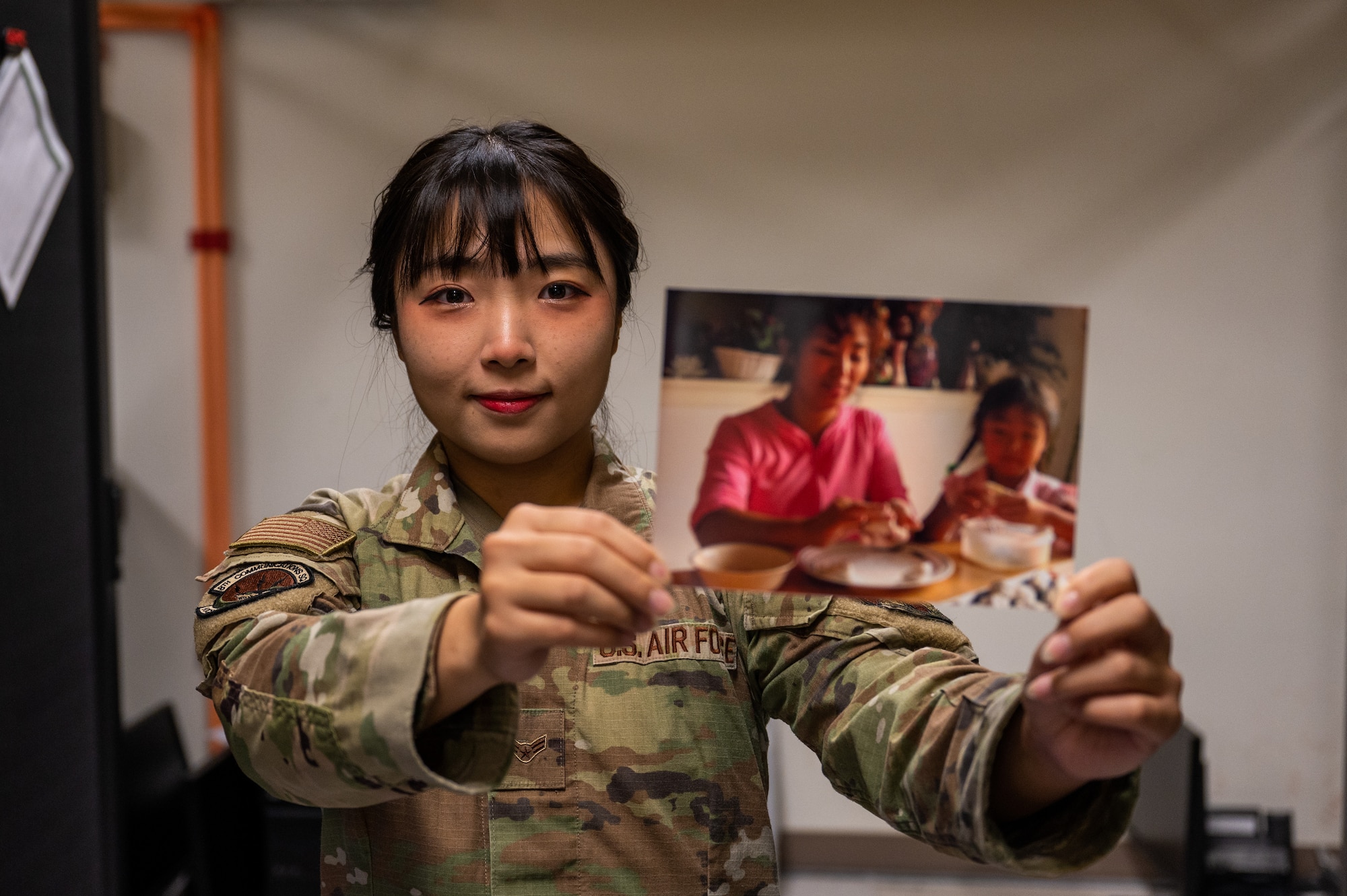 Airman 1st Class Hyeon Jung holds up a photo of her making rice cakes with her mother when she was a child during Chuseok.