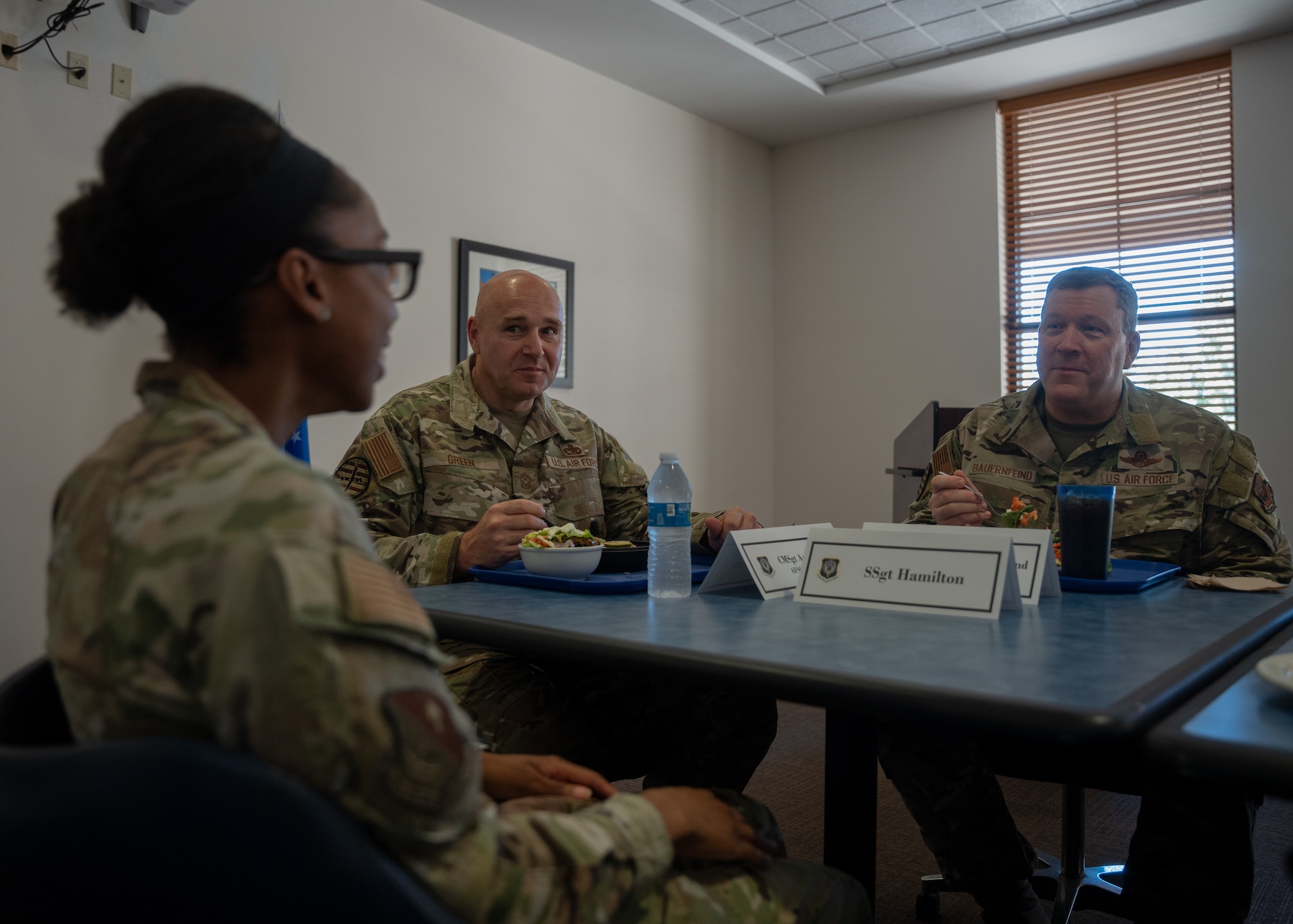 Three service members sit at a table in the dining facility discussing medical challenges at Cannon Air Force Base.