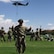 Man wearing U.S. Army uniform stands in front of a group of U.S. Army soldiers and a helicopter.