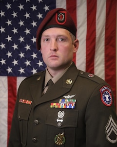 Man in U.S. Army uniform standing in front of an American Flag